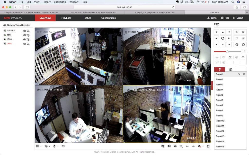 Hikvision CCTV system live view interface on a computer screen, showing four camera feeds monitoring a shop interior including entrance, back office, and parts area.