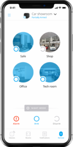 Smartphone screen showing a security app interface for a car showroom. The app displays four monitored areas: Safe, Shop, Office, and Tech room, each represented by a circular image. At the bottom, there are options for Alarm, Arm, and Disarm, with “Partially Armed” status shown at the top.